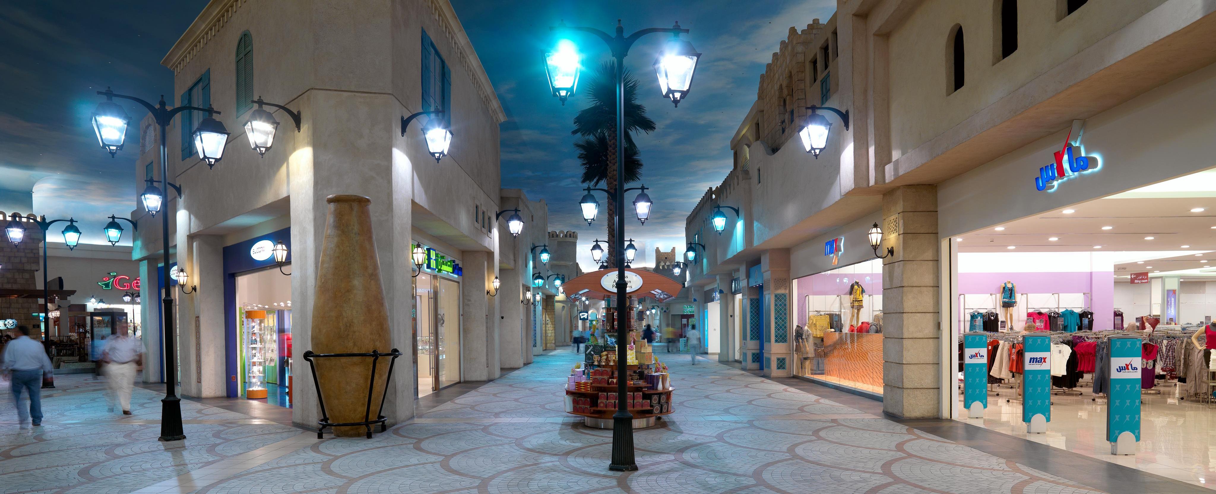 Interior del Ibn Battuta Mall con suelos decorados con motivos geométricos, farolas negras y una fachada arquitectónica de estilo tradicional. 