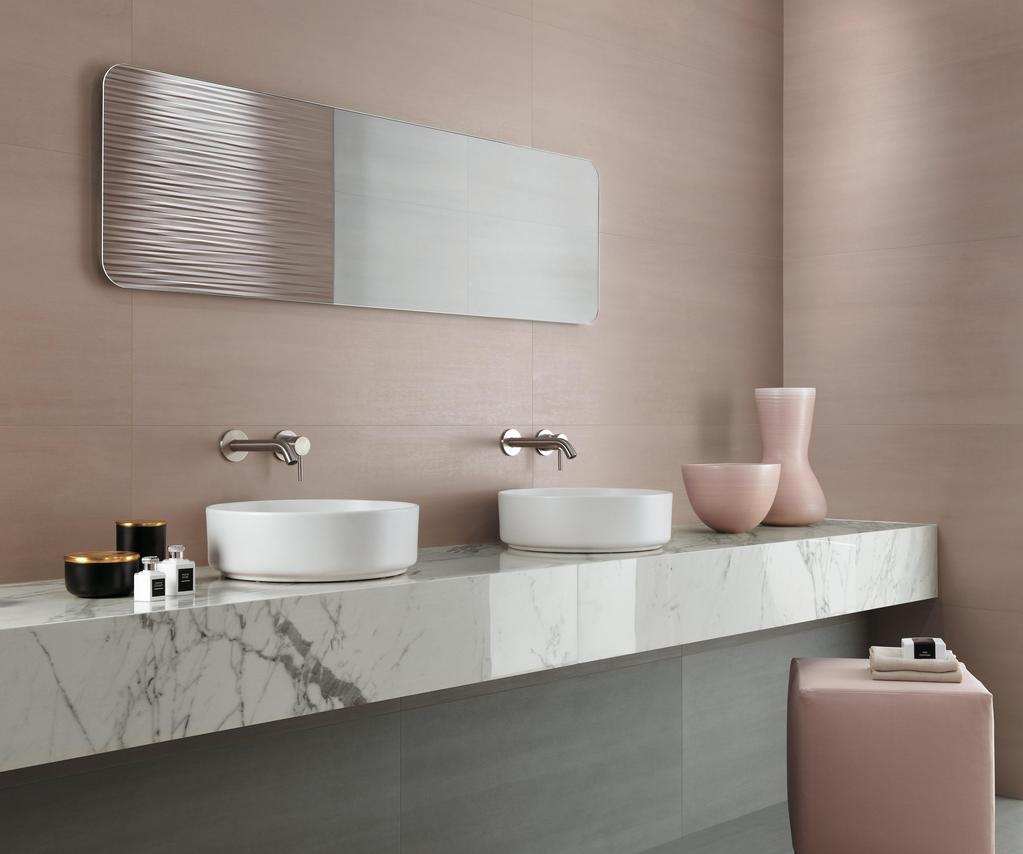 Salle de bain avec carrelage rose poudré, double lavabo sur plan en marbre blanc et accessoires décoratifs assortis.