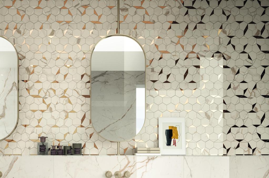 Bagno con piastrelle in mosaico bianco e oro, due specchi ovali e un lavandino in marmo bianco. 