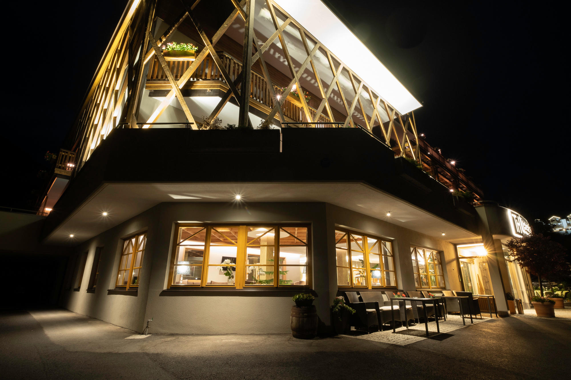 Illuminated exterior of the Hotel Terentnerhof at night with wooden architecture and large windows.