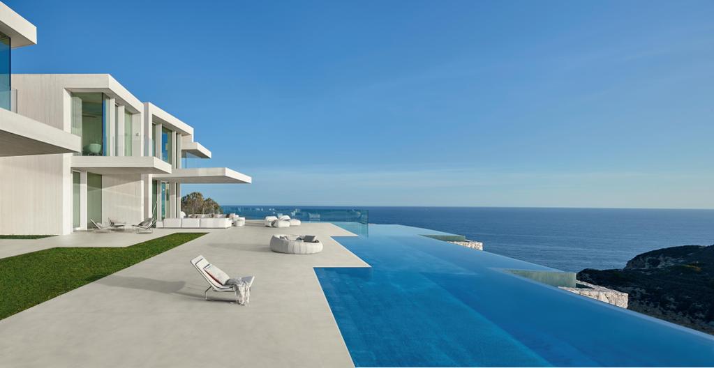 Villa moderne avec un sol en carreaux effet micro-ciment et une piscine à débordement avec vue sur la mer