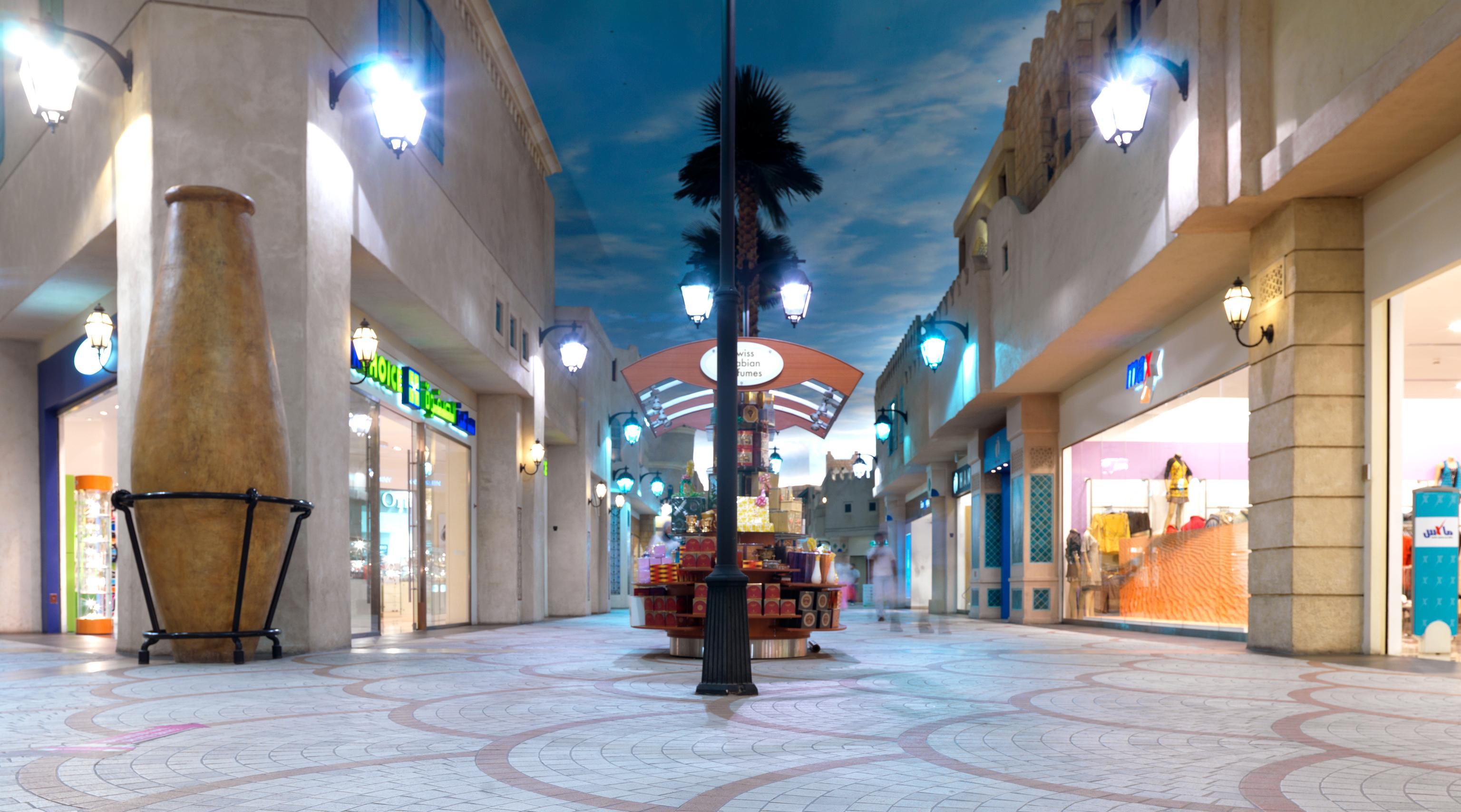 Interior del Ibn Battuta Mall con suelos decorados con motivos geométricos, farolas negras y una fachada arquitectónica de estilo tradicional. 