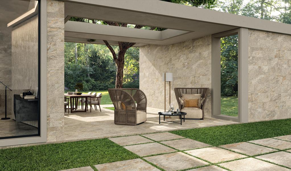 Terrazza con piastrelle per esterni antiscivolo effetto pietra bianco, arredamento in vimini con cuscini, tavolino e zona pranzo sotto una tettoia.