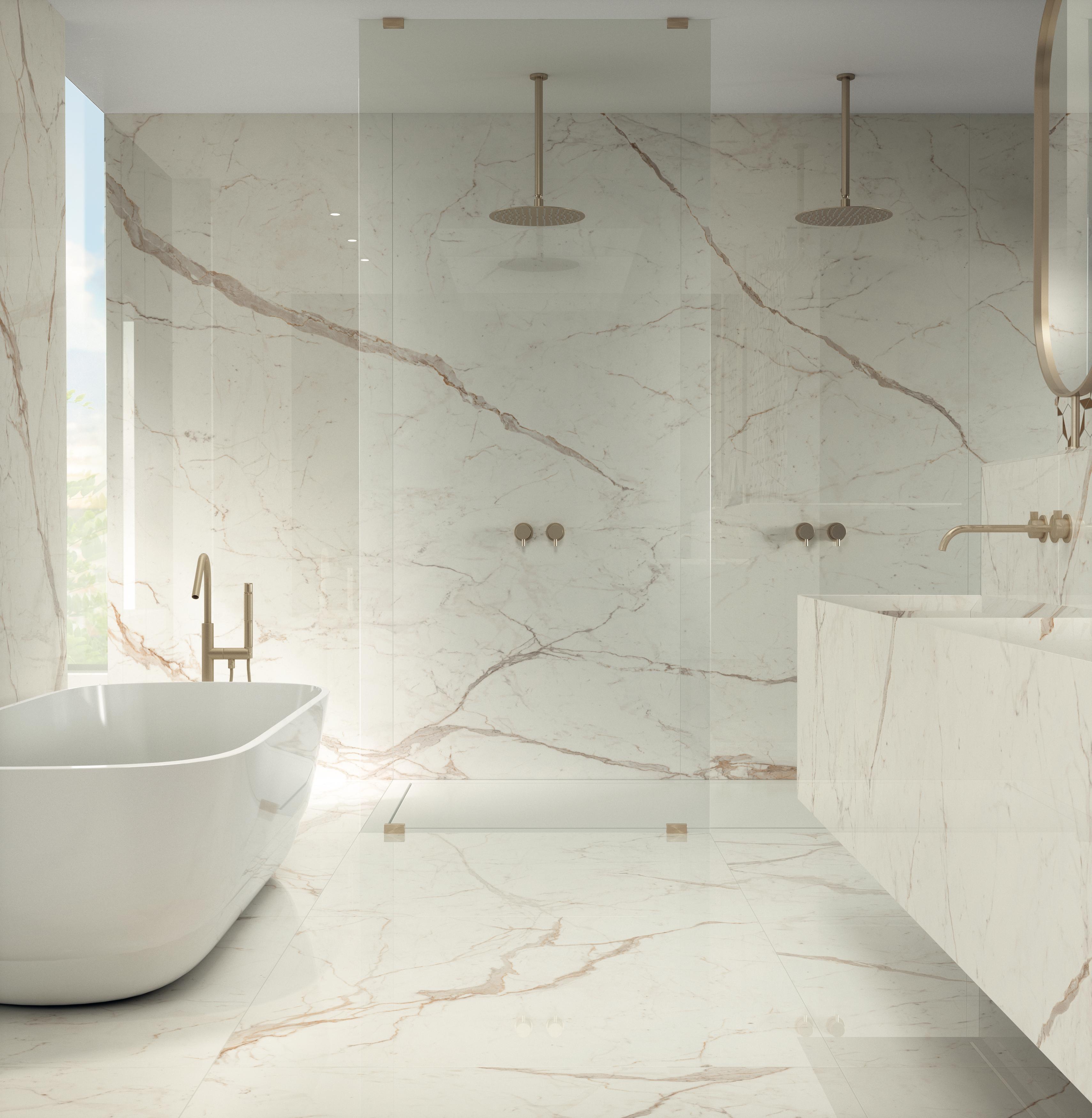 Luxurious bathroom with large format white marble effect tiles, with a freestanding bathtub, double showers and golden taps.