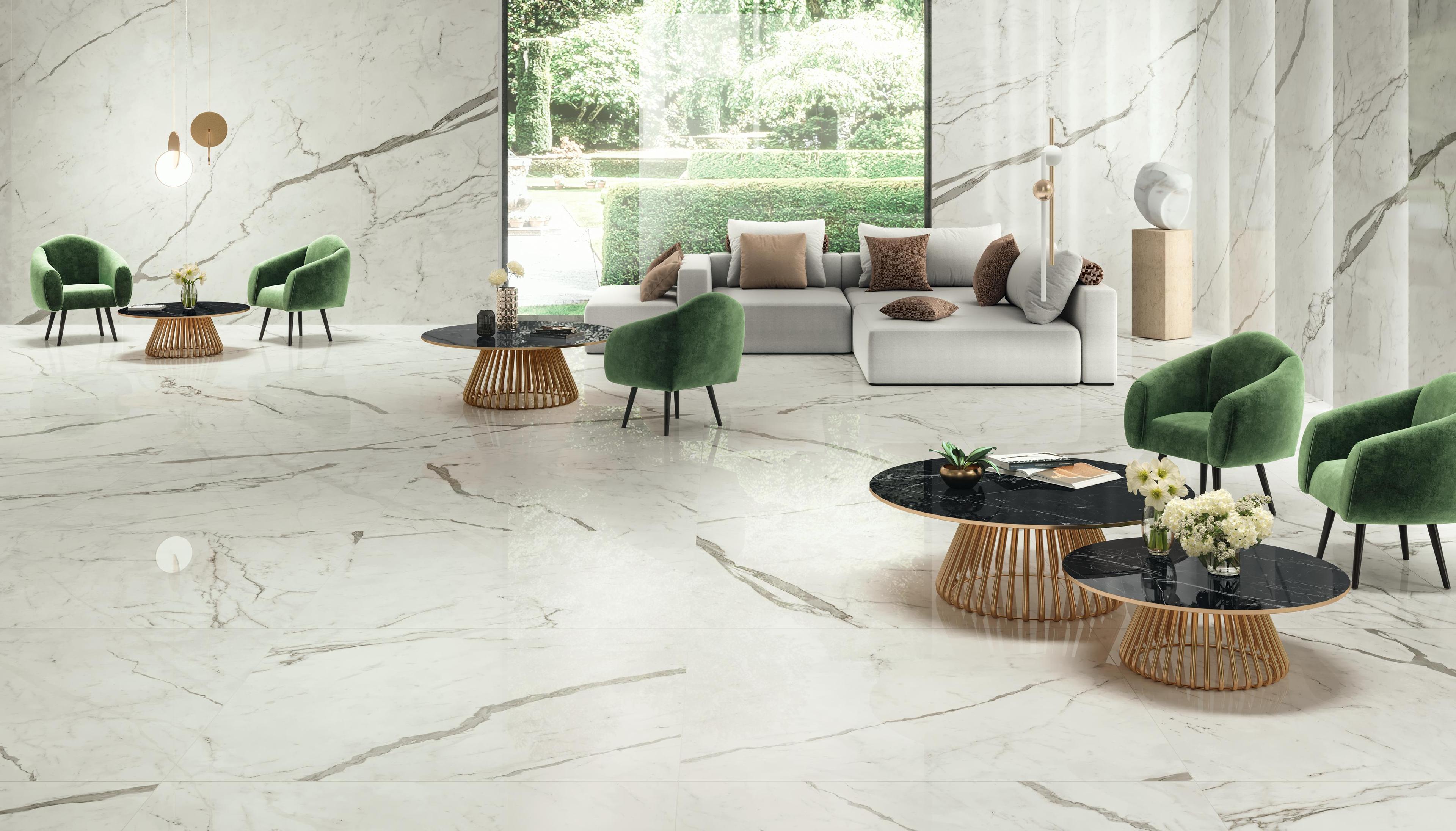 Großes Wohnzimmer mit weißem Marmorboden, grünen Sesseln, grauem Sofa und schwarzen Tischen.