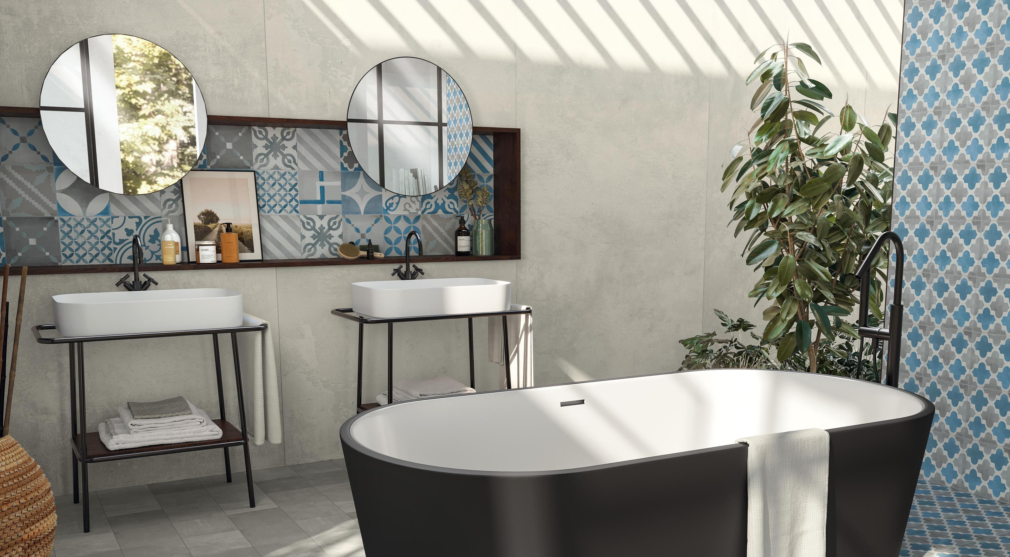 Bathroom with porcelain stoneware floor effect cement, black bath, white washbasins and blue decorative tiles.