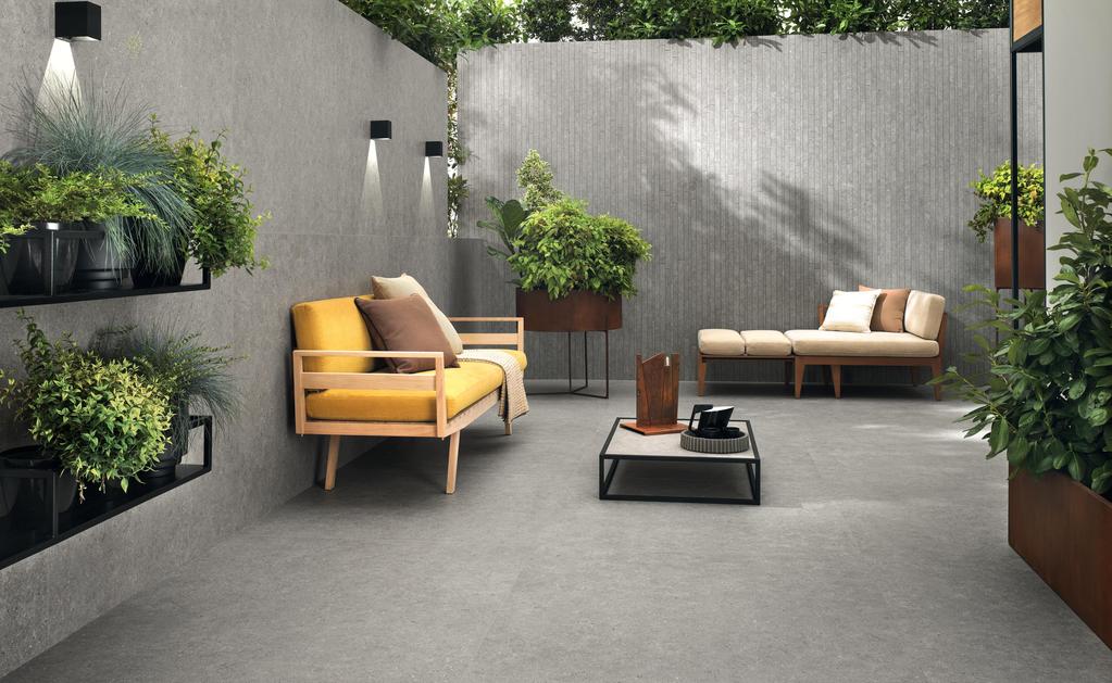 Außenbereich mit grauen Fliesen, moderne Einrichtung mit gelben und beigen Sofa, schwarzem Couchtisch und Dekorationen mit Pflanzen.