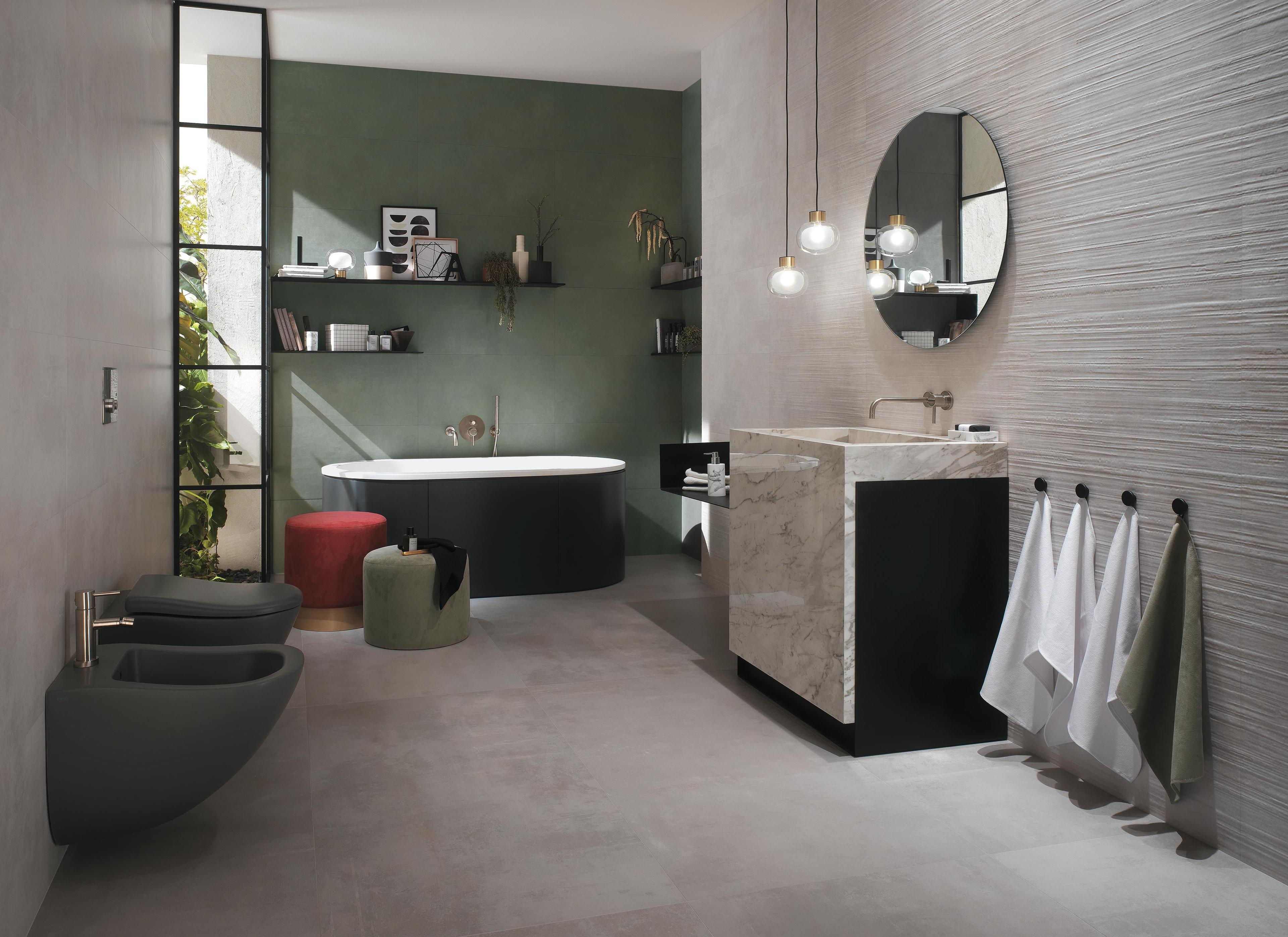 Modern bathroom with porcelain tile floor effect cement, black bath, marble sink and green walls.