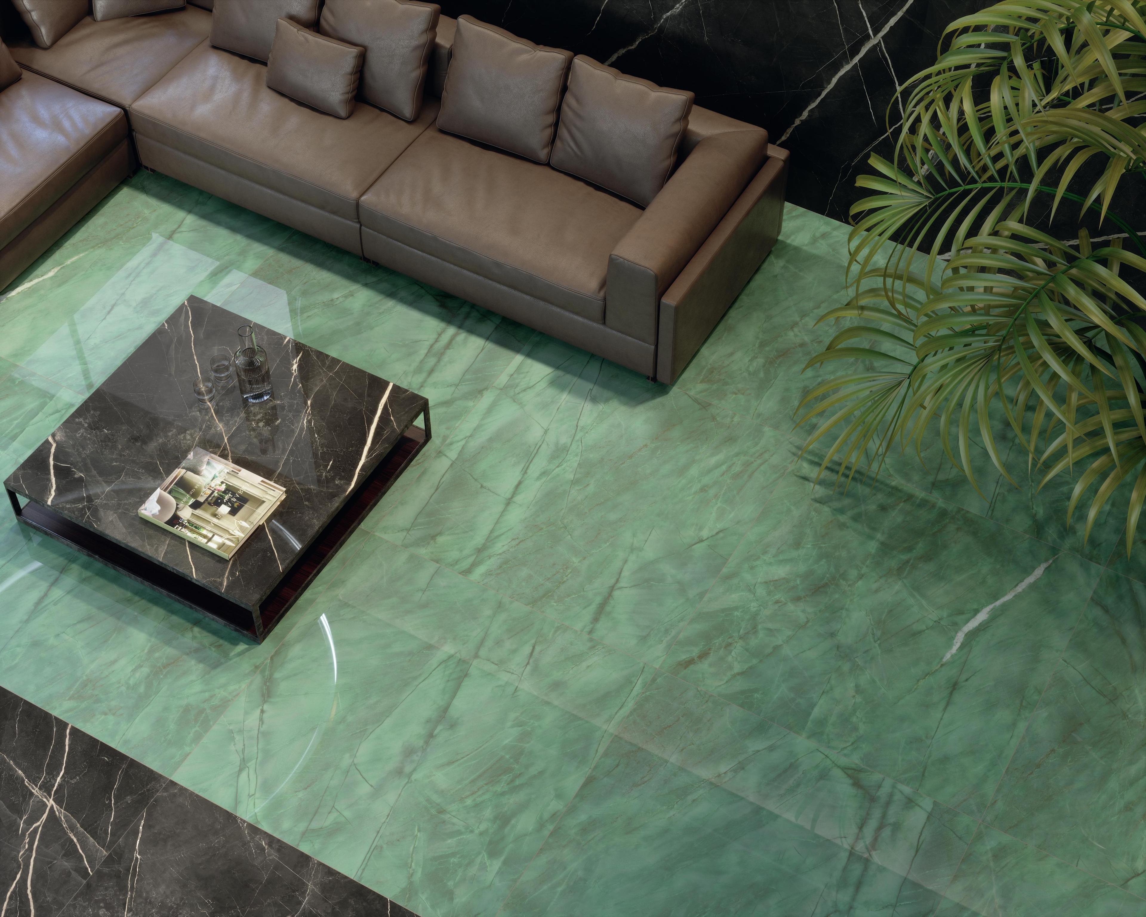 Salón con suelo de gres porcelánico efecto mármol verde, sofá marrón, mesa de café negra con encimera de mármol y una planta decorativa.