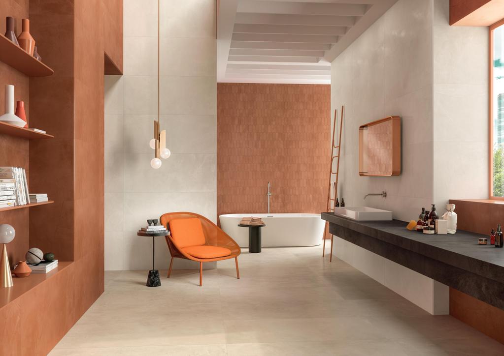 Salle de bain moderne avec carrelage rose et terre cuite effet résine, baignoire, lavabo sur plan sombre et fauteuil orange.