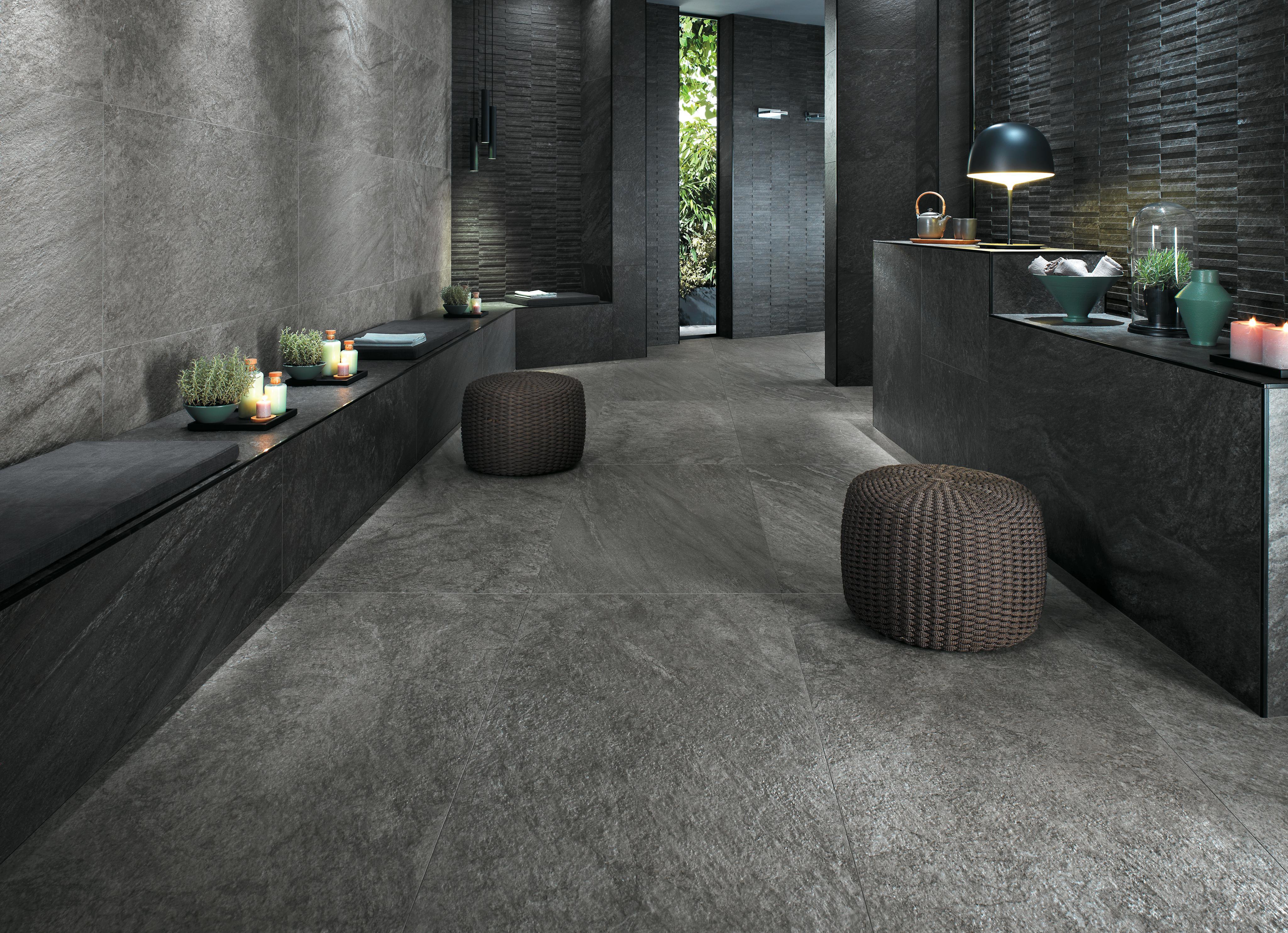 Interno moderno con pavimento e pareti rivestite in gres porcellanato Atlas Concorde Brave, caratterizzati da tonalità scure. 