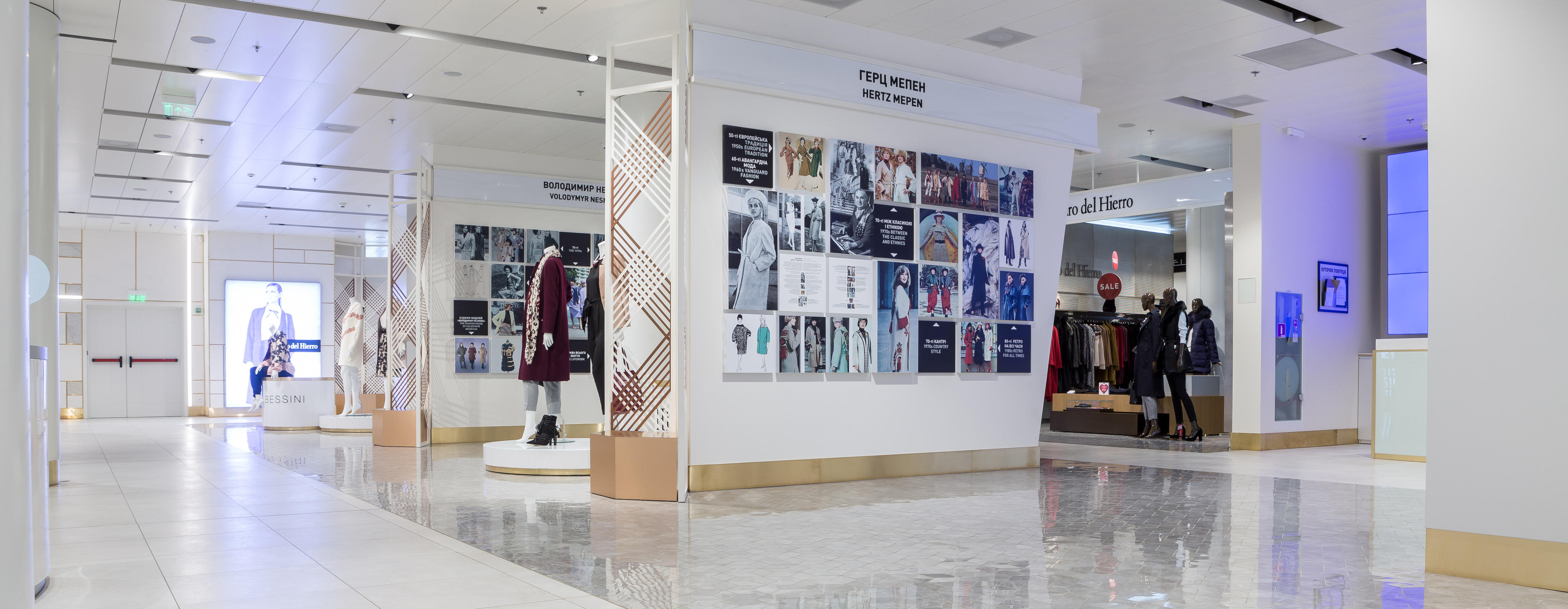 Interno di un centro commerciale moderno con pavimenti lucidi e manichini con abbigliamento in esposizione. 