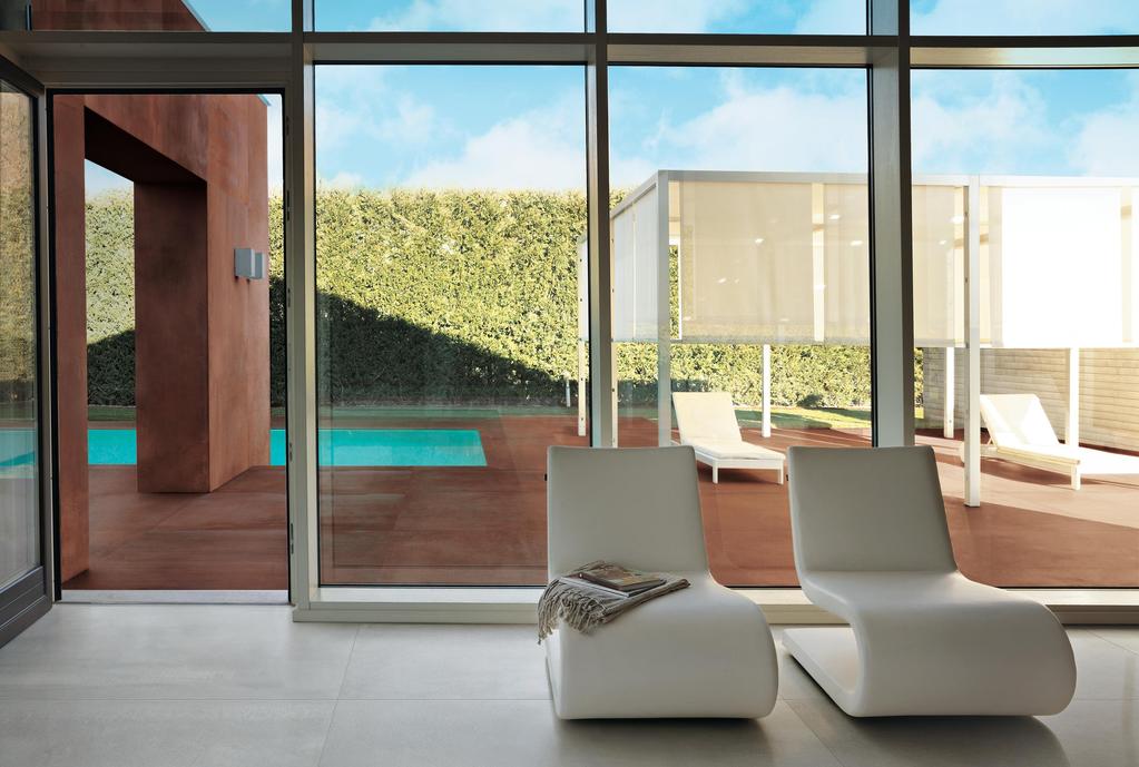 Innen mit grauen Fliesen, weißen Stühlen mit modernem Design und großen Fenstern mit Blick auf eine Terrasse mit Pool.