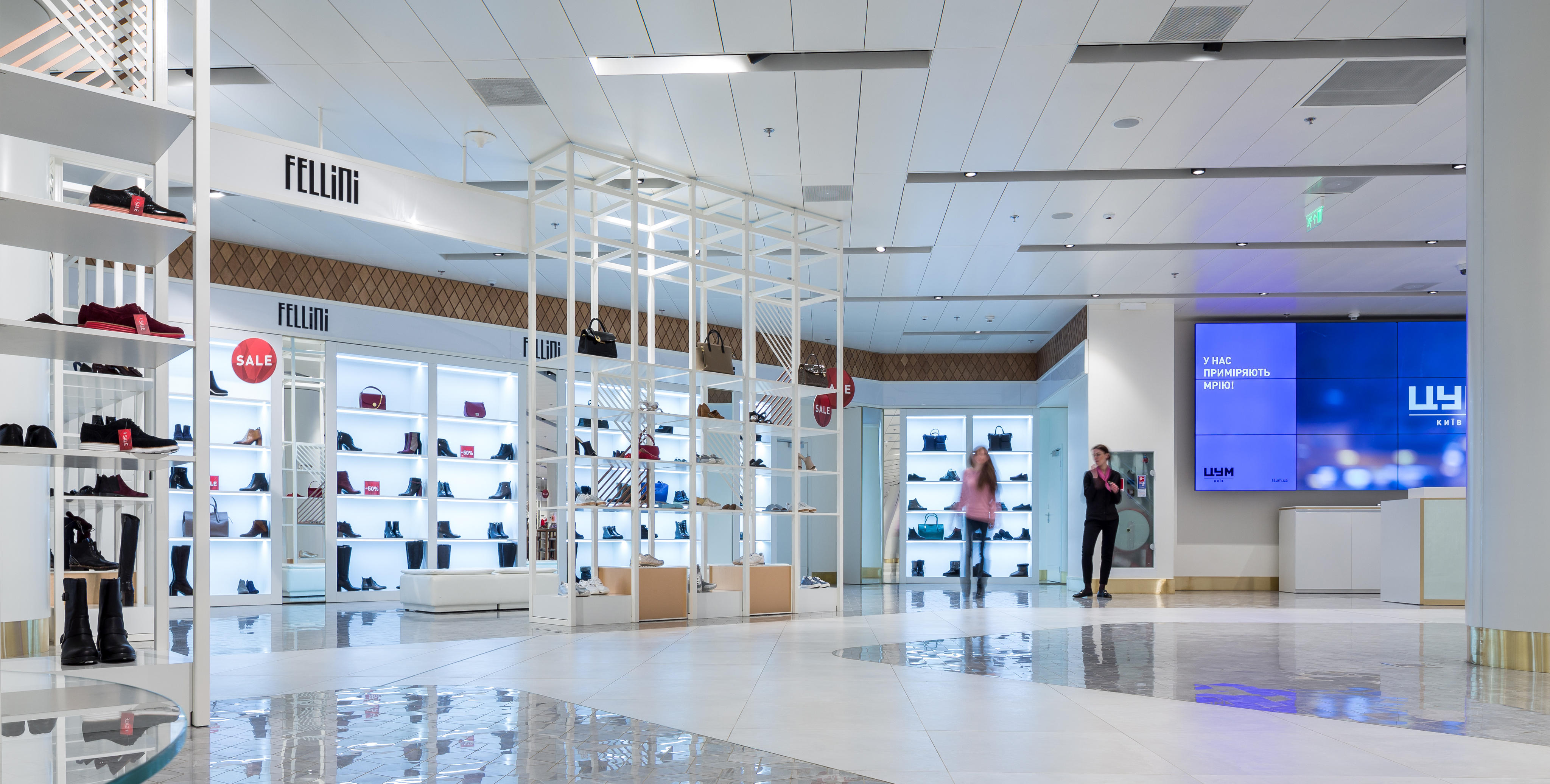 Interno di un centro commerciale moderno estetico con pavimenti lucidati, scaffali con scarpe e borse, e la gente a piedi.