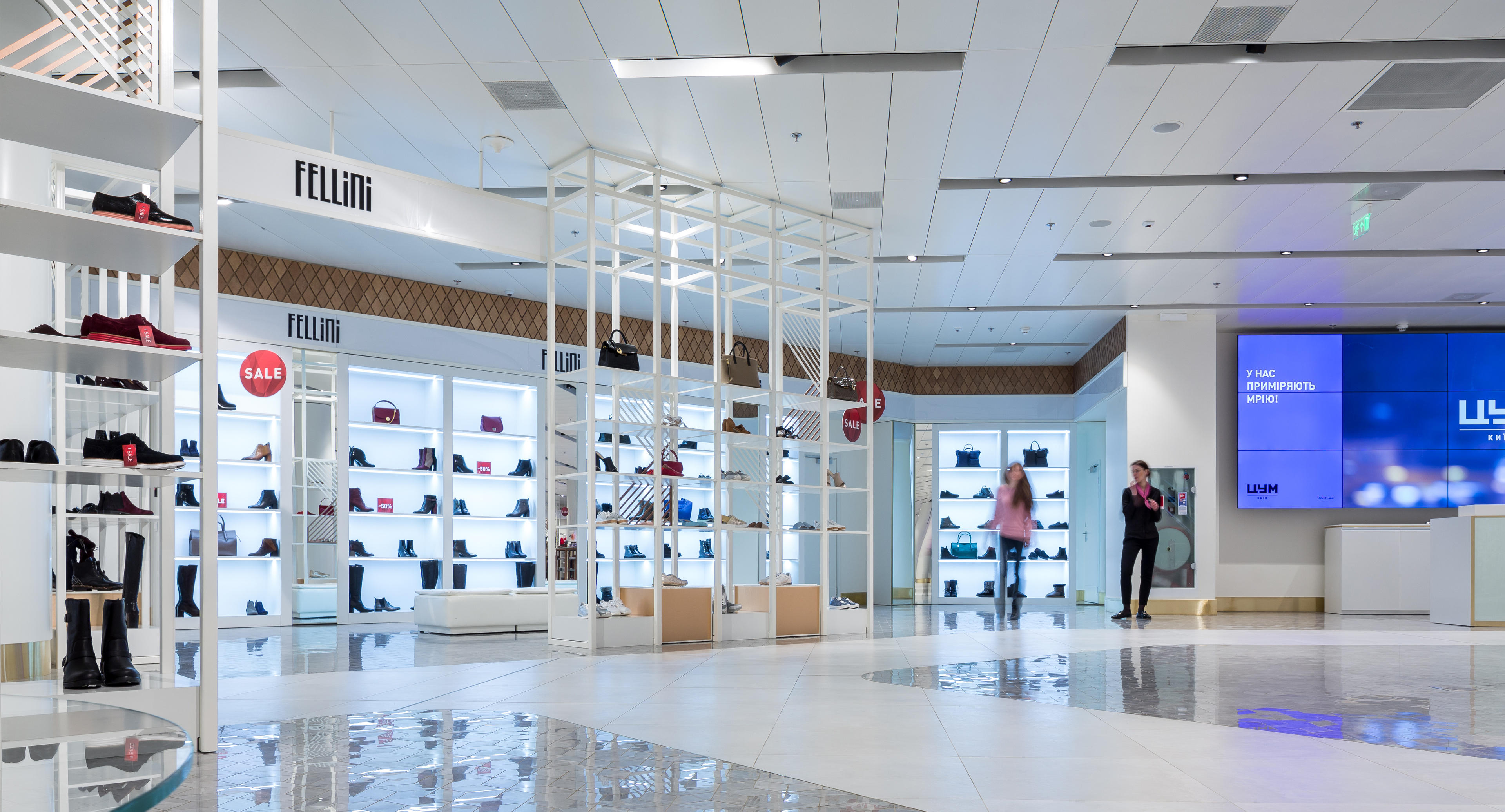 Innenraum eines modernen ästhetischen Einkaufszentrum mit polierten Böden, Regale mit Schuhen und Taschen, und die Menschen zu Fuß.
