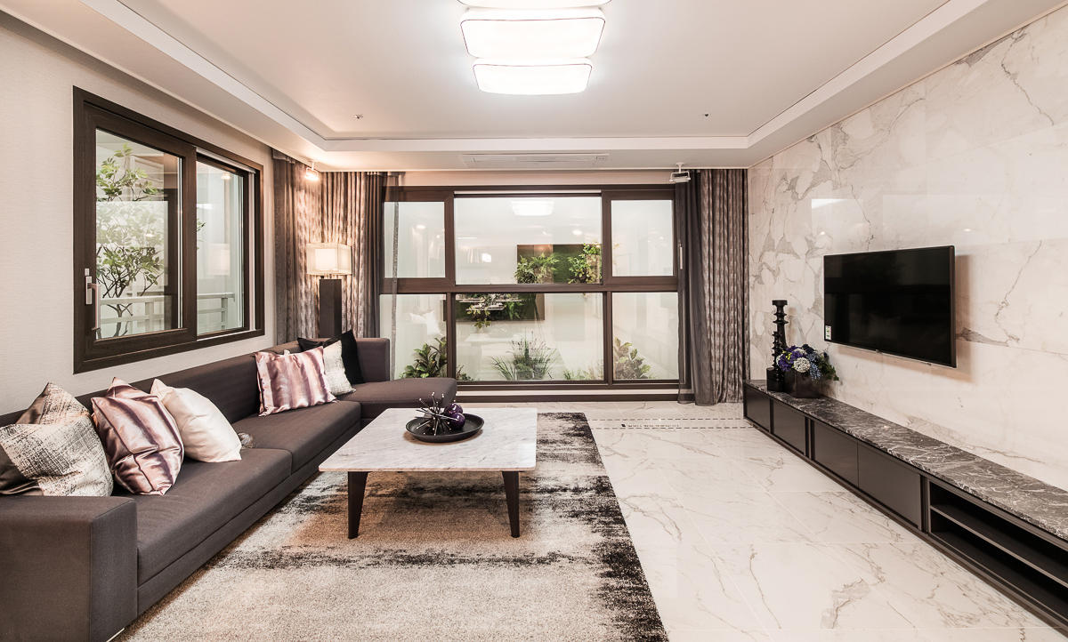 Salon d’un luxueux appartement coréen avec de grandes fenêtres offrant une vue sur le jardin intérieur.
