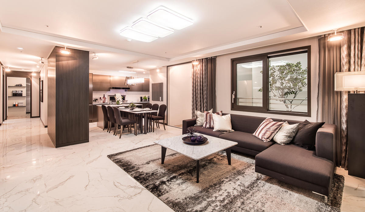 Intérieur d’un appartement coréen luxueux avec un mobilier moderne, canapé d’angle, table à manger élégante et sols en marbre.
